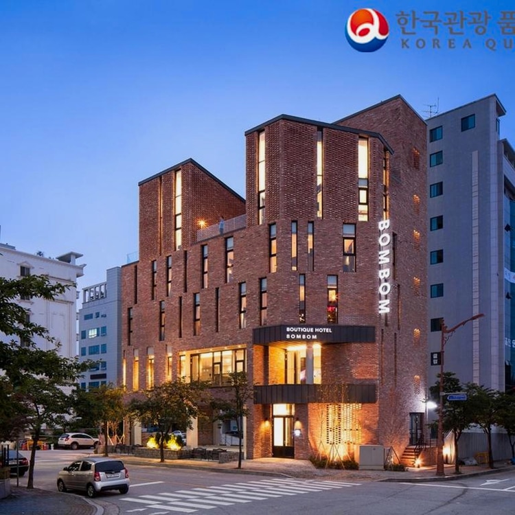 조명이 켜진 붉은 벽돌 건물의 호텔 외관입니다.