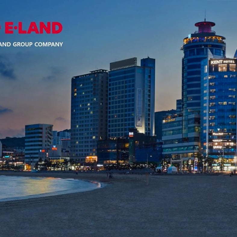해변 모래사장 너머로 보이는 건물들의 야경 전경입니다.