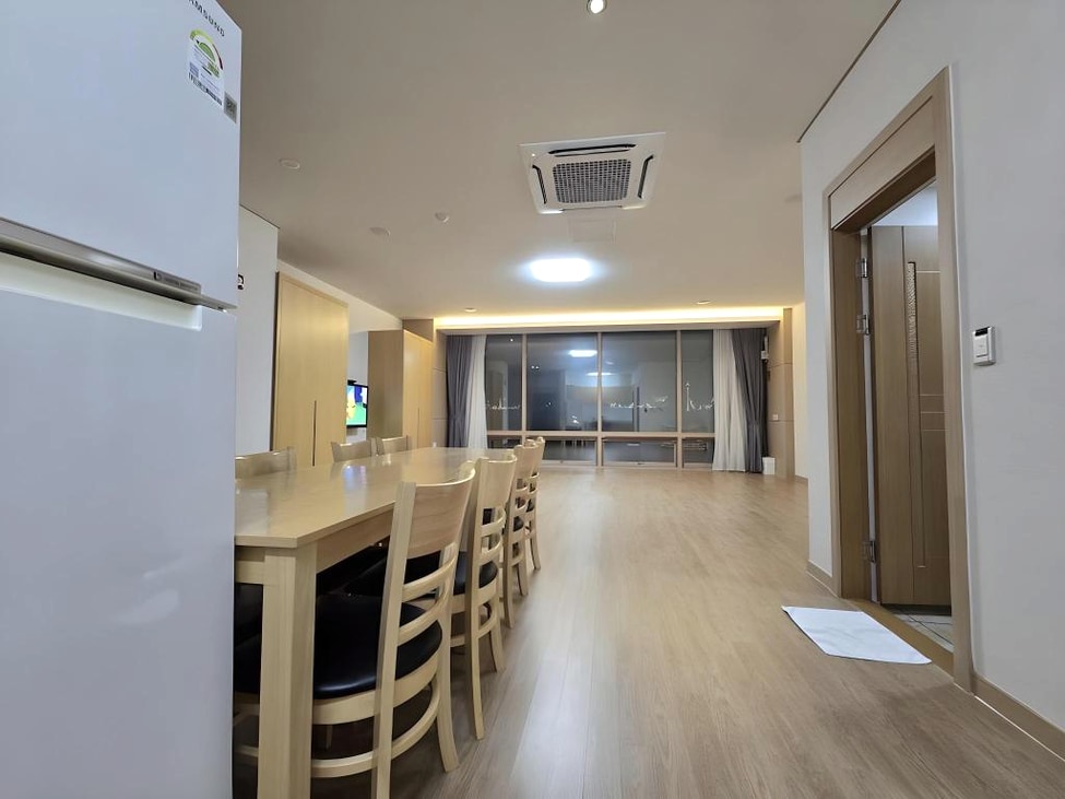 긴 식탁과 넓은 마루가 조성된 객실 실내 공간입니다.