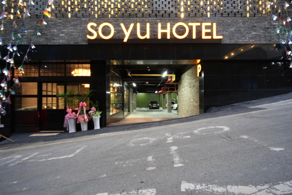SO YU HOTEL 간판과 주차장 입구가 보이는 건물 외관입니다.